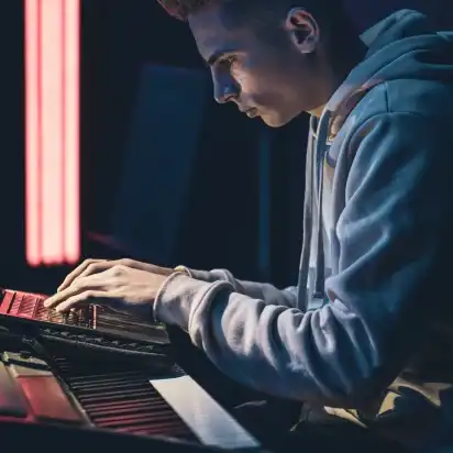 Independant musician sitting at his desk and using his audio mixer to mix up a song