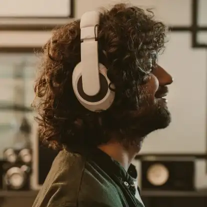 Very satisfied man listening to music on his white over ears closed headphones